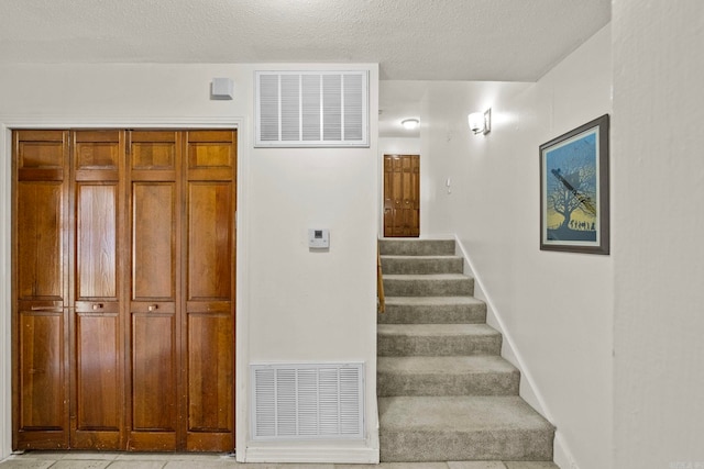 staircase with tile patterned floors and a textured ceiling