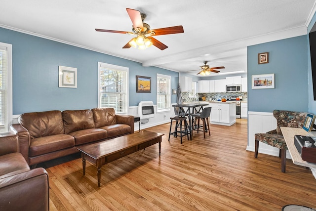 living room with heating unit, light hardwood / wood-style flooring, ceiling fan, and crown molding