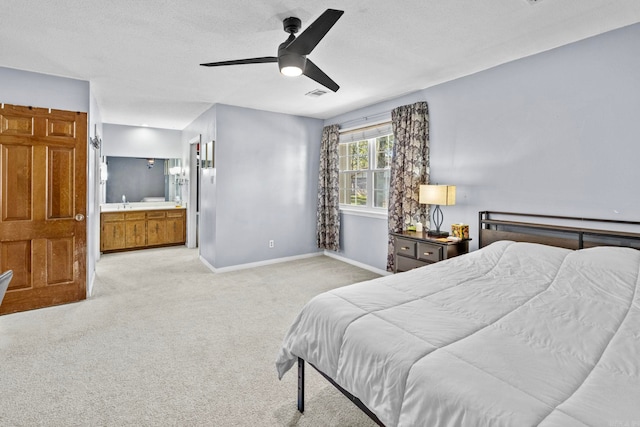 carpeted bedroom with a textured ceiling, ensuite bathroom, and ceiling fan