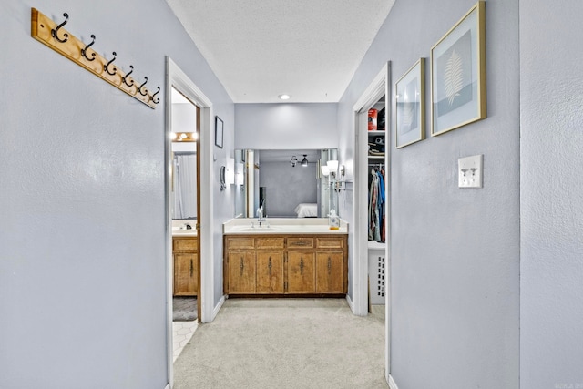 hall with light colored carpet and a textured ceiling