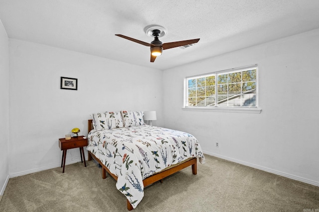 carpeted bedroom with ceiling fan and a textured ceiling