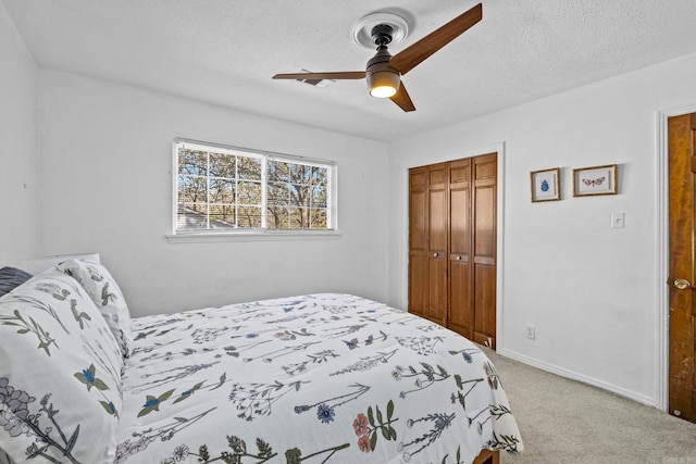 bedroom with ceiling fan, light colored carpet, a textured ceiling, and a closet