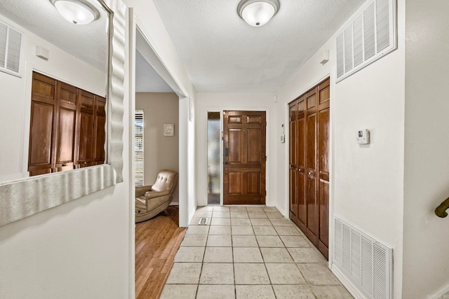 corridor featuring light hardwood / wood-style flooring and a textured ceiling