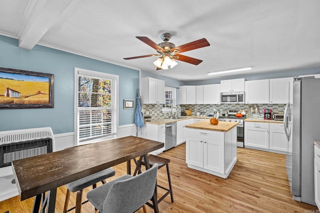 kitchen with white cabinets, appliances with stainless steel finishes, light wood-type flooring, and crown molding