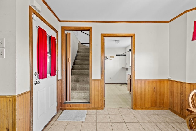 foyer with wooden walls, crown molding, and light tile patterned flooring