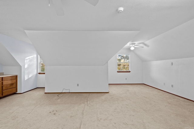 bonus room with light colored carpet, plenty of natural light, lofted ceiling, and ceiling fan