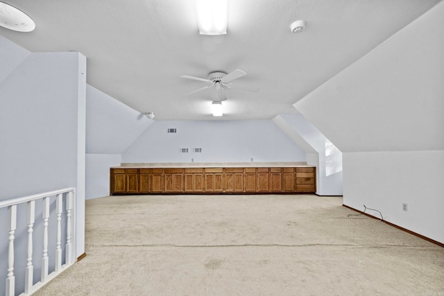 bonus room featuring a textured ceiling, light colored carpet, ceiling fan, and lofted ceiling