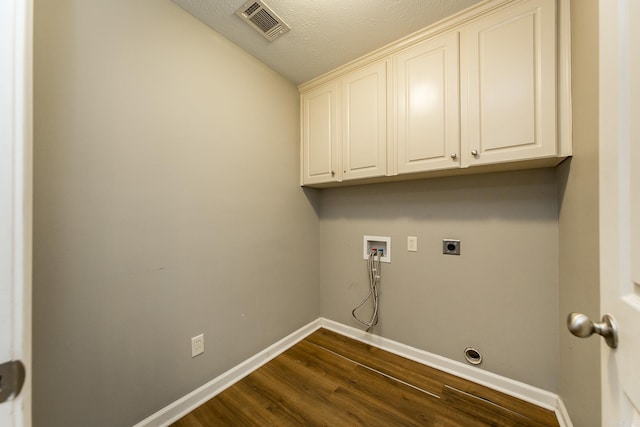 laundry area featuring cabinets, hookup for a washing machine, a textured ceiling, electric dryer hookup, and dark wood-type flooring