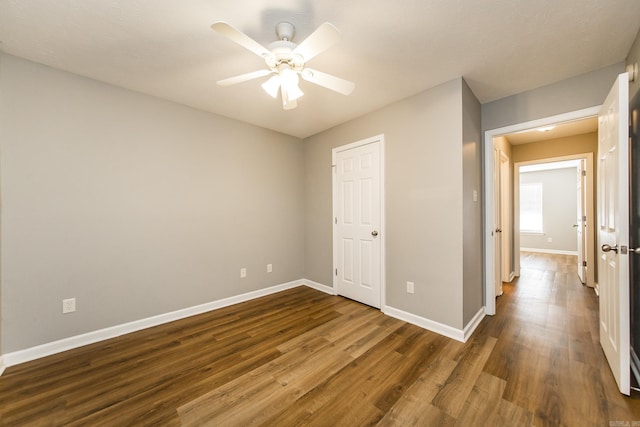 unfurnished bedroom with ceiling fan and dark wood-type flooring