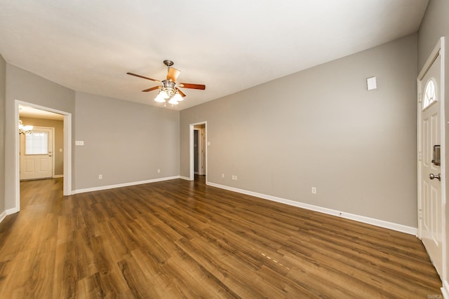 interior space featuring ceiling fan with notable chandelier and dark hardwood / wood-style flooring