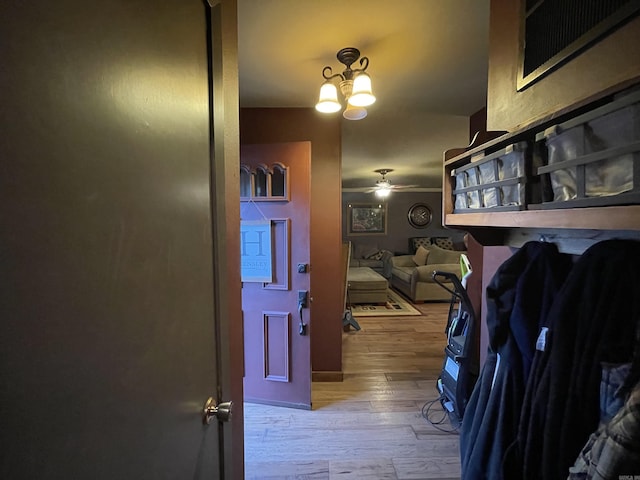 hallway with light hardwood / wood-style floors, an inviting chandelier, and crown molding