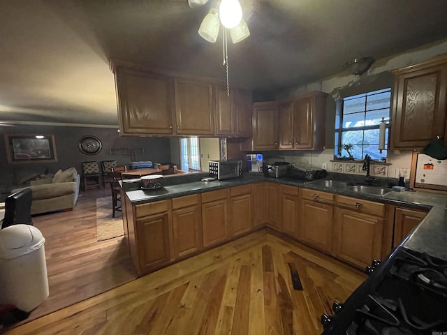 kitchen featuring ceiling fan, light wood-type flooring, kitchen peninsula, and sink