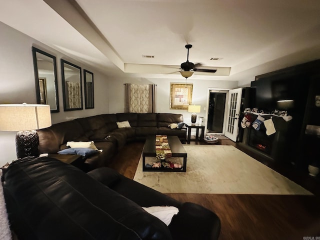 living room featuring a tray ceiling, hardwood / wood-style flooring, and ceiling fan