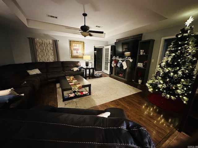 living room featuring hardwood / wood-style flooring, ceiling fan, and a tray ceiling