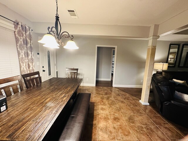 dining area featuring decorative columns, tile patterned floors, and an inviting chandelier