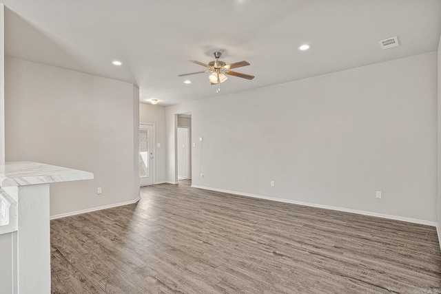 unfurnished living room featuring ceiling fan and dark wood-type flooring