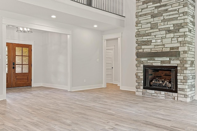 unfurnished living room with a fireplace, light hardwood / wood-style flooring, and a notable chandelier