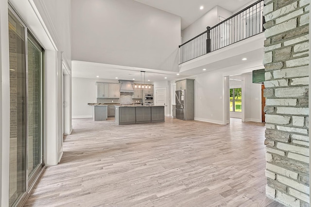 unfurnished living room with a towering ceiling and light wood-type flooring