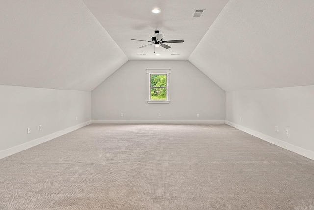 additional living space featuring a textured ceiling, light colored carpet, ceiling fan, and lofted ceiling