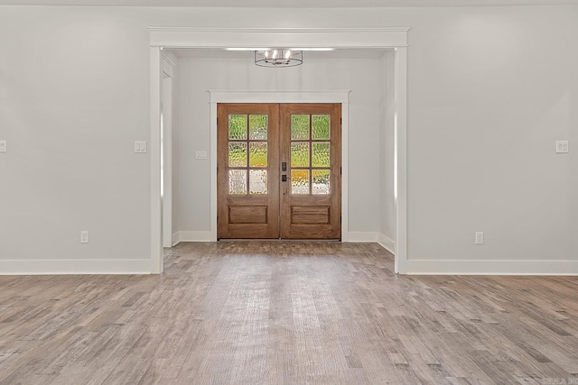 entrance foyer featuring french doors, an inviting chandelier, and light wood-type flooring