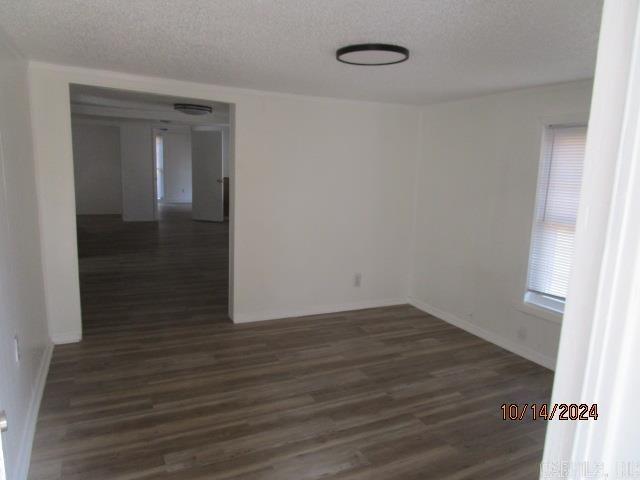 unfurnished room with a textured ceiling and dark hardwood / wood-style flooring