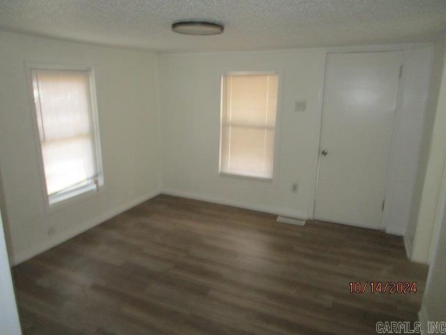 spare room with dark wood-type flooring and a textured ceiling