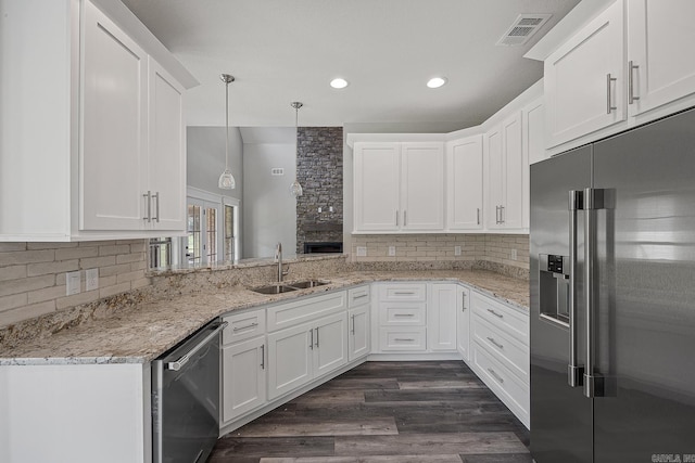 kitchen with appliances with stainless steel finishes, sink, decorative light fixtures, dark hardwood / wood-style floors, and white cabinetry