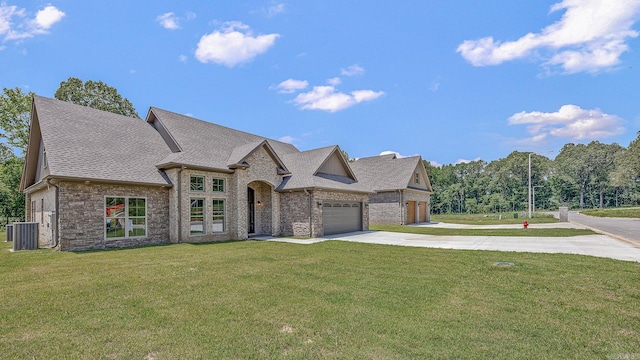 french country style house with a garage, a front yard, and central AC