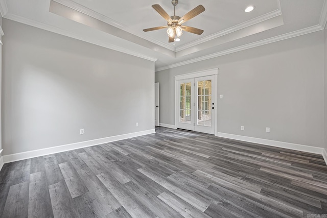 empty room with dark wood-type flooring, crown molding, and a tray ceiling