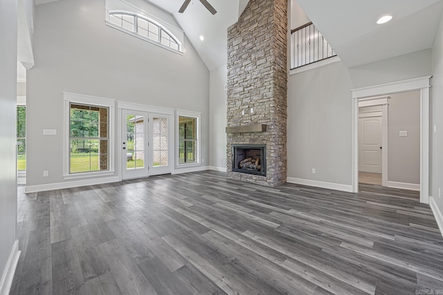 unfurnished living room featuring a fireplace, dark hardwood / wood-style flooring, high vaulted ceiling, and ceiling fan