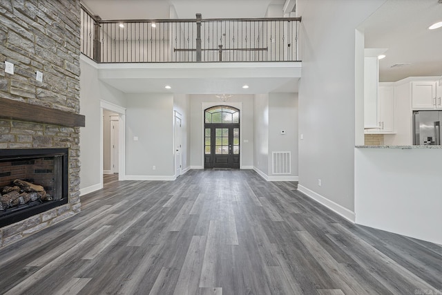 foyer featuring a fireplace, dark hardwood / wood-style flooring, a towering ceiling, and french doors