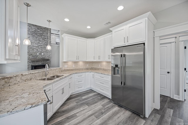 kitchen with high quality fridge, white cabinets, and hanging light fixtures