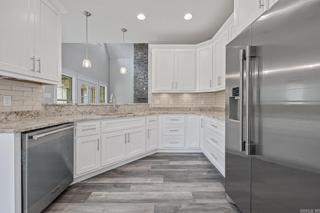 kitchen featuring white cabinets, light hardwood / wood-style floors, light stone countertops, and appliances with stainless steel finishes