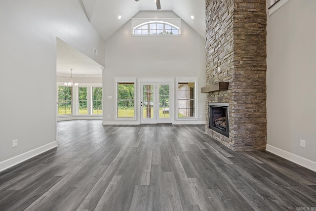 unfurnished living room with a fireplace, ceiling fan with notable chandelier, dark wood-type flooring, and high vaulted ceiling