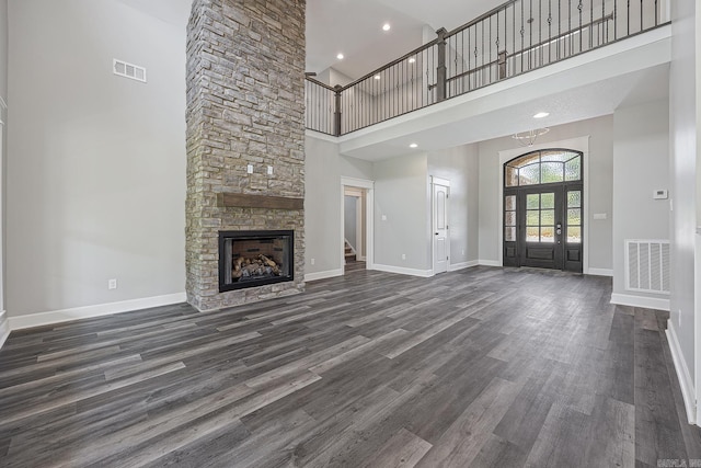 unfurnished living room featuring a fireplace, a high ceiling, dark hardwood / wood-style flooring, and french doors