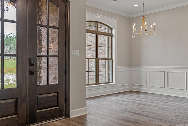 foyer entrance featuring hardwood / wood-style flooring, a notable chandelier, a healthy amount of sunlight, and crown molding