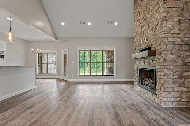 unfurnished living room with hardwood / wood-style floors, a stone fireplace, and high vaulted ceiling