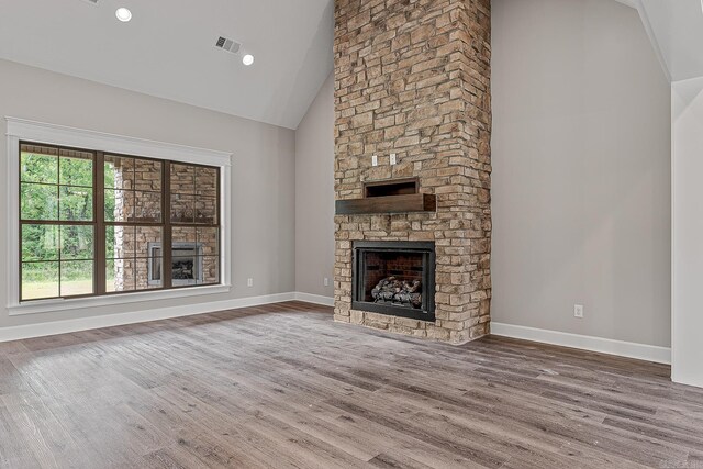 unfurnished living room with a stone fireplace, high vaulted ceiling, and hardwood / wood-style flooring