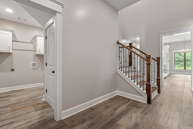 stairway with a chandelier and hardwood / wood-style floors