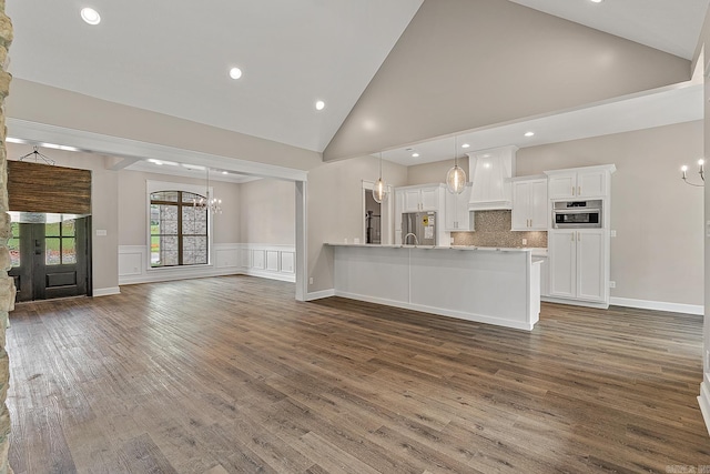 unfurnished living room featuring dark hardwood / wood-style flooring, high vaulted ceiling, and an inviting chandelier