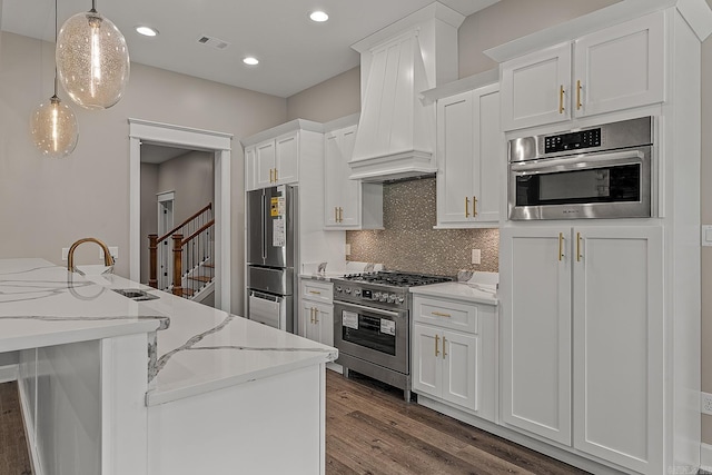 kitchen with dark hardwood / wood-style flooring, custom exhaust hood, premium appliances, white cabinetry, and hanging light fixtures