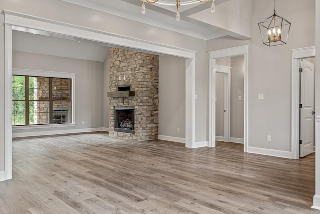 unfurnished living room featuring a chandelier, a fireplace, ornamental molding, and hardwood / wood-style flooring