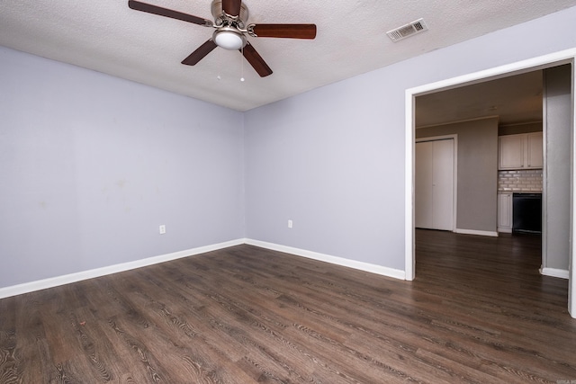 spare room with a textured ceiling, ceiling fan, and dark wood-type flooring