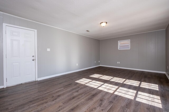 unfurnished room with a textured ceiling, dark hardwood / wood-style floors, and ornamental molding