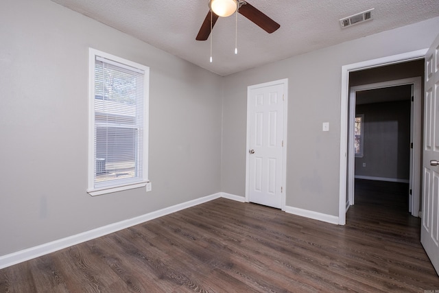 empty room with a textured ceiling, dark hardwood / wood-style floors, and ceiling fan