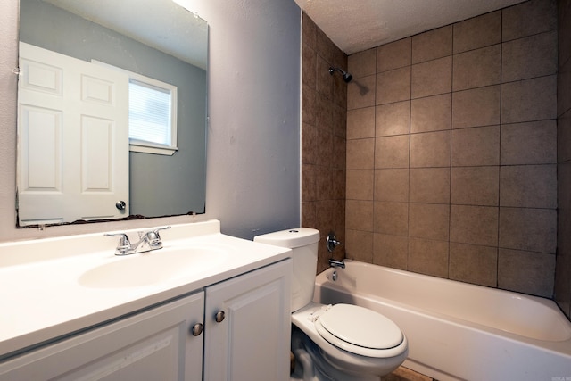 full bathroom with a textured ceiling, vanity, toilet, and tiled shower / bath