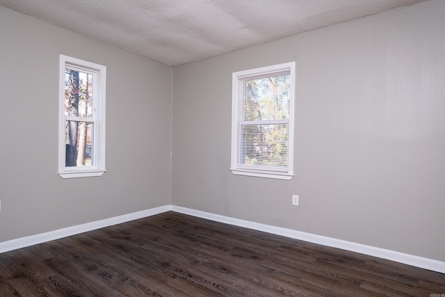 spare room featuring dark hardwood / wood-style floors, a textured ceiling, and a wealth of natural light