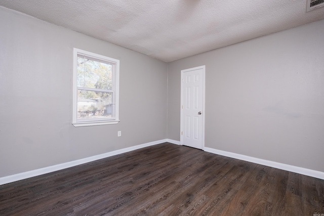 empty room with dark hardwood / wood-style flooring and a textured ceiling