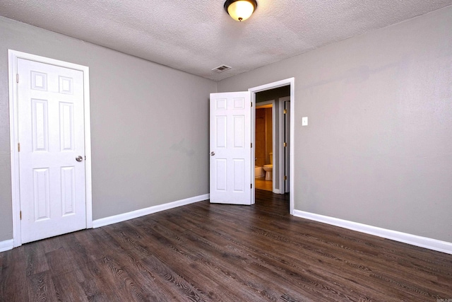 unfurnished bedroom with a textured ceiling and dark hardwood / wood-style floors