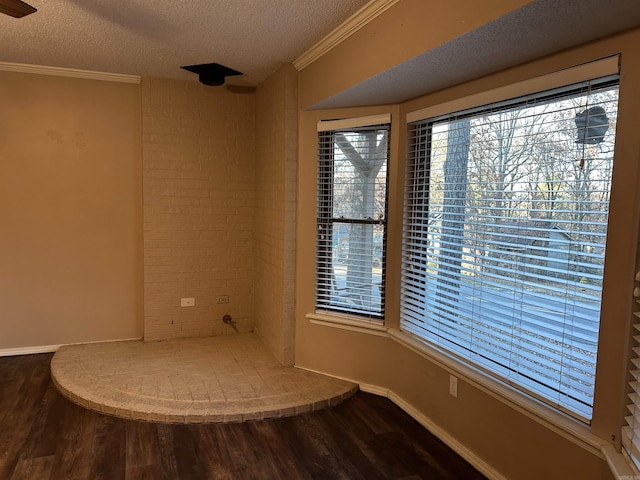 empty room featuring hardwood / wood-style flooring, ornamental molding, and a textured ceiling